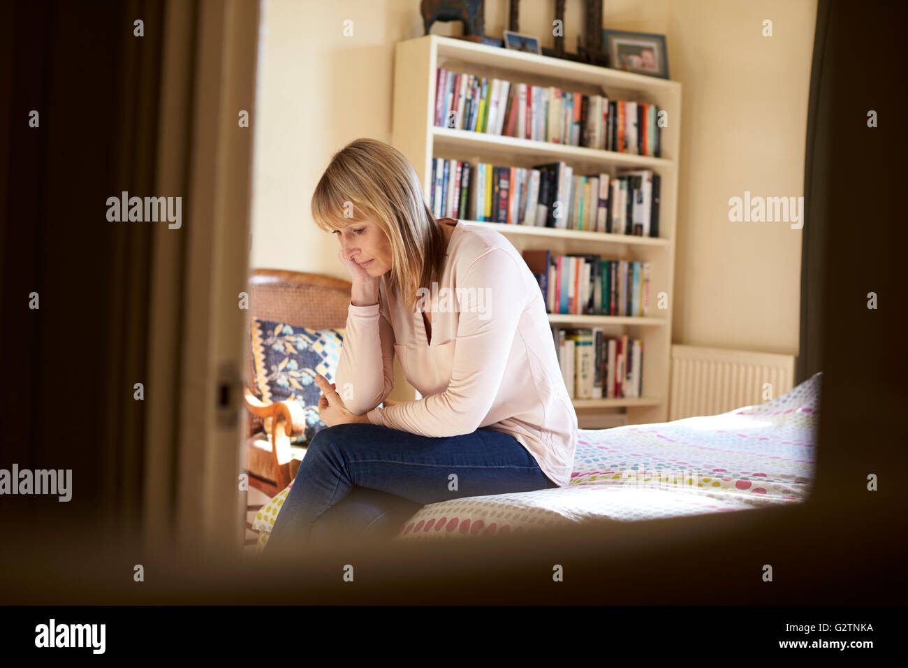 Premuto donna matura seduta sul letto di casa Foto Stock