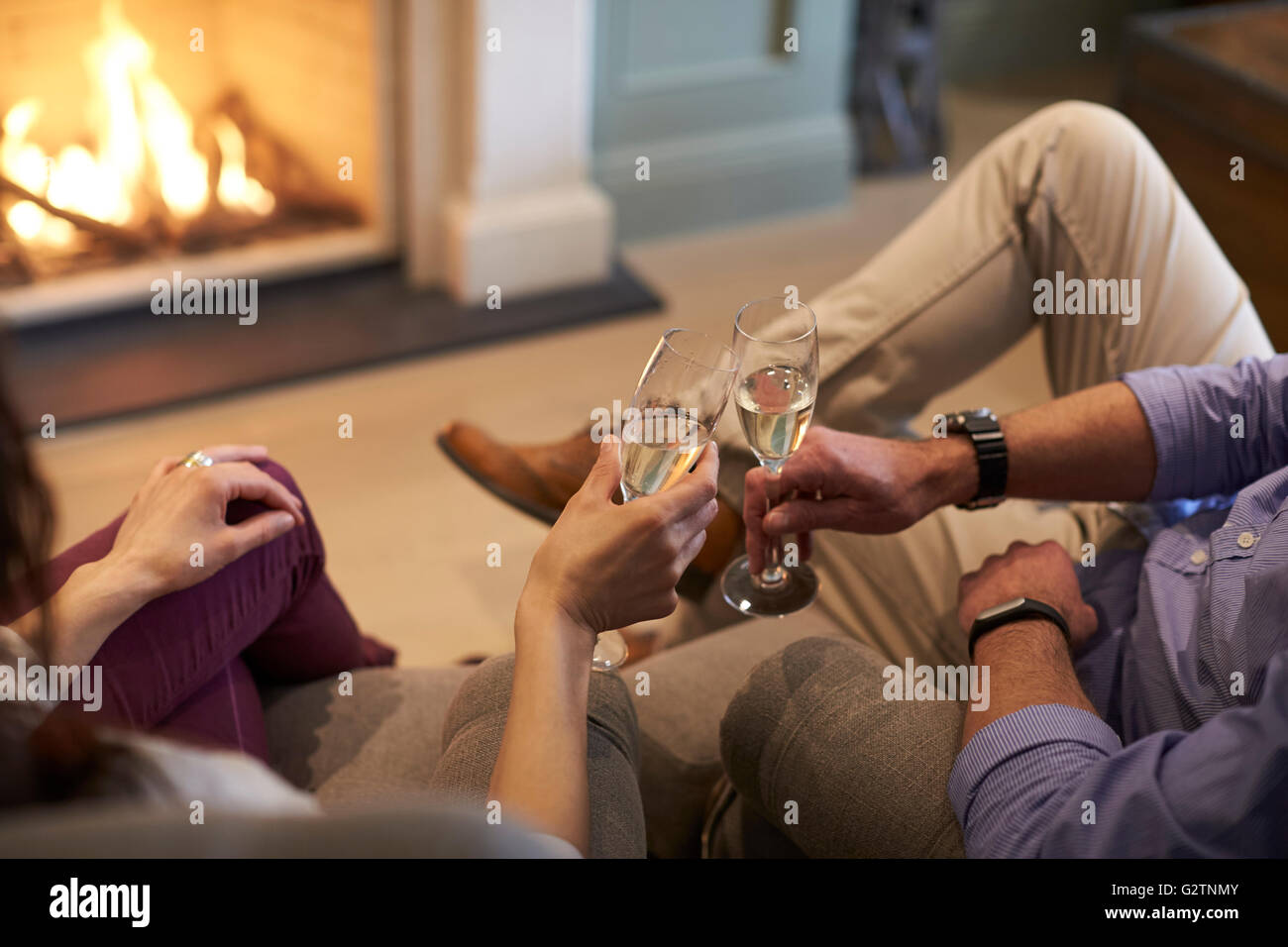 Chiusura del giovane seduto da Fire rendendo Toast Champagne Foto Stock