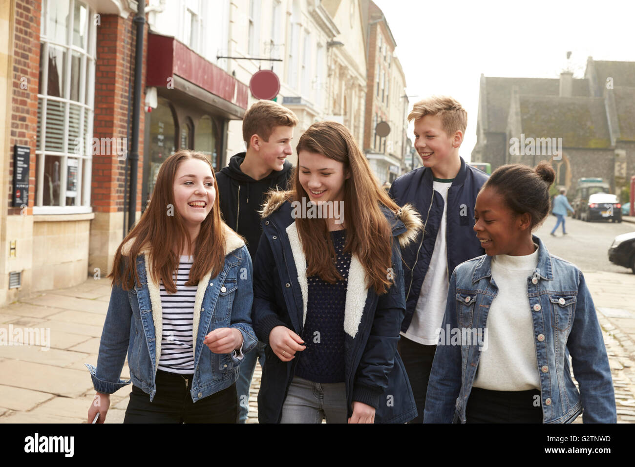 Gruppo di adolescenti a piedi lungo la strada nel contesto urbano Foto Stock
