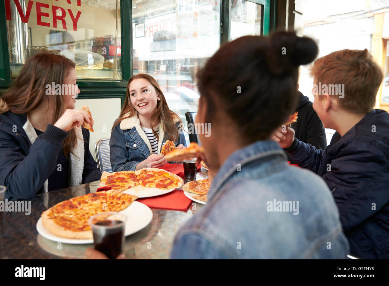 Un gruppo di adolescenti di mangiare la pizza in Cafe Foto Stock