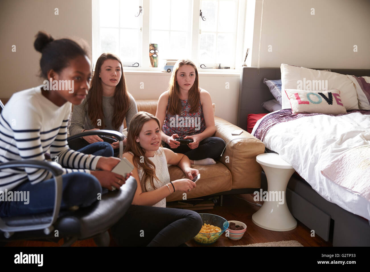 Un gruppo di ragazze adolescenti la riproduzione del video gioco in camera da letto Foto Stock