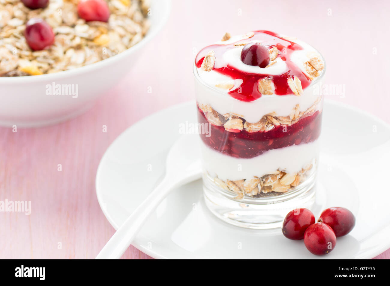 Un vetro con yogurt e muesli su un piattino. Foto Stock