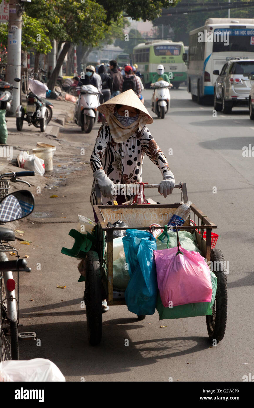 Vecchia donna raccoglie roba con risciò bicicletta come rifiuti nel parco pubblico, a Saigon, Vietnam. Foto Stock