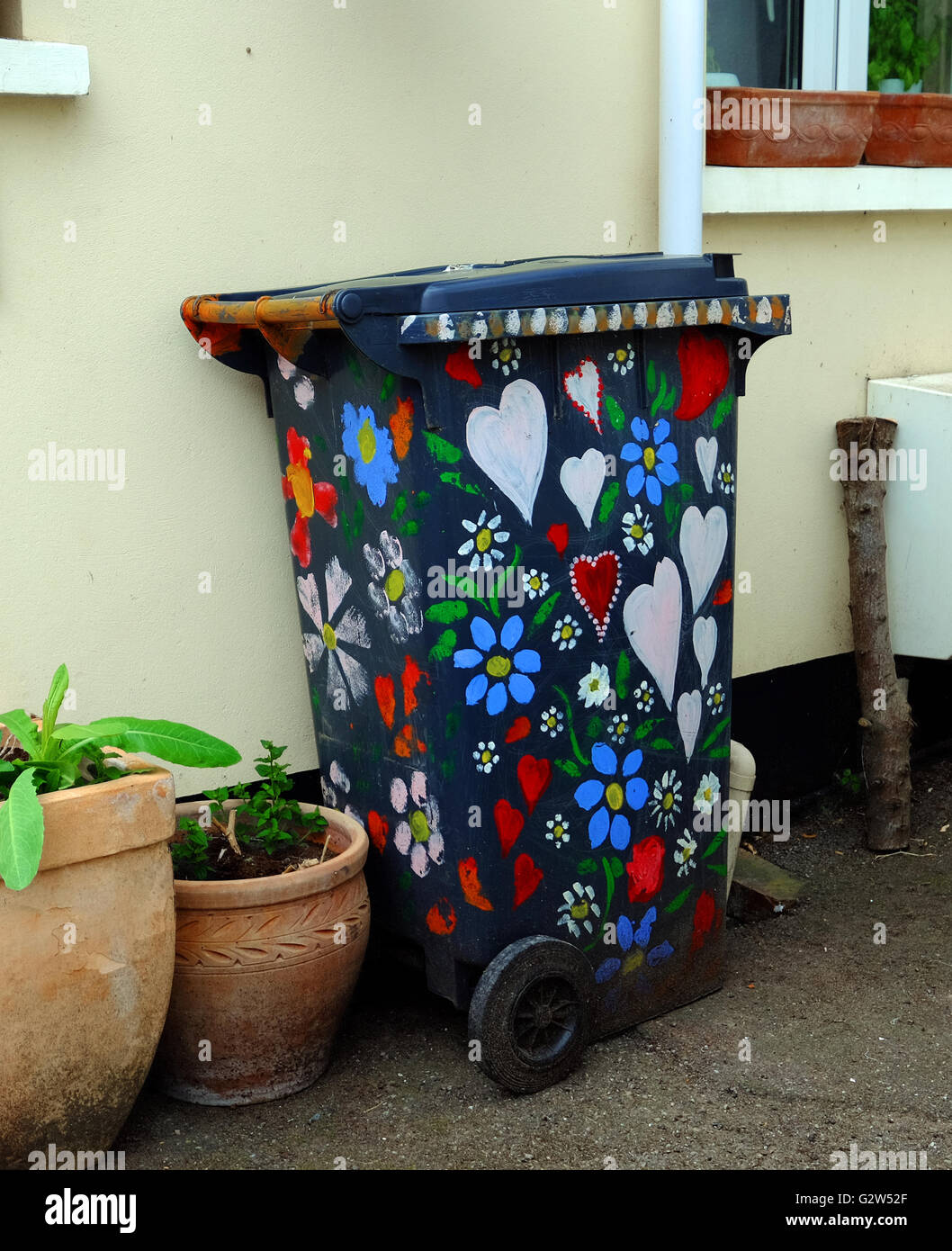 Un bidone della spazzatura, dipinte con fiori colorati e i cuori. Foto Stock