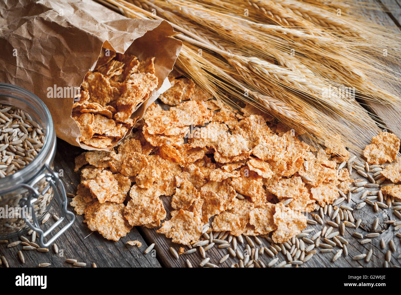 Cereali Fiocchi di frumento, picchi di segale e grano sul vecchio tavola in legno rustico. Retrò tonica. Foto Stock