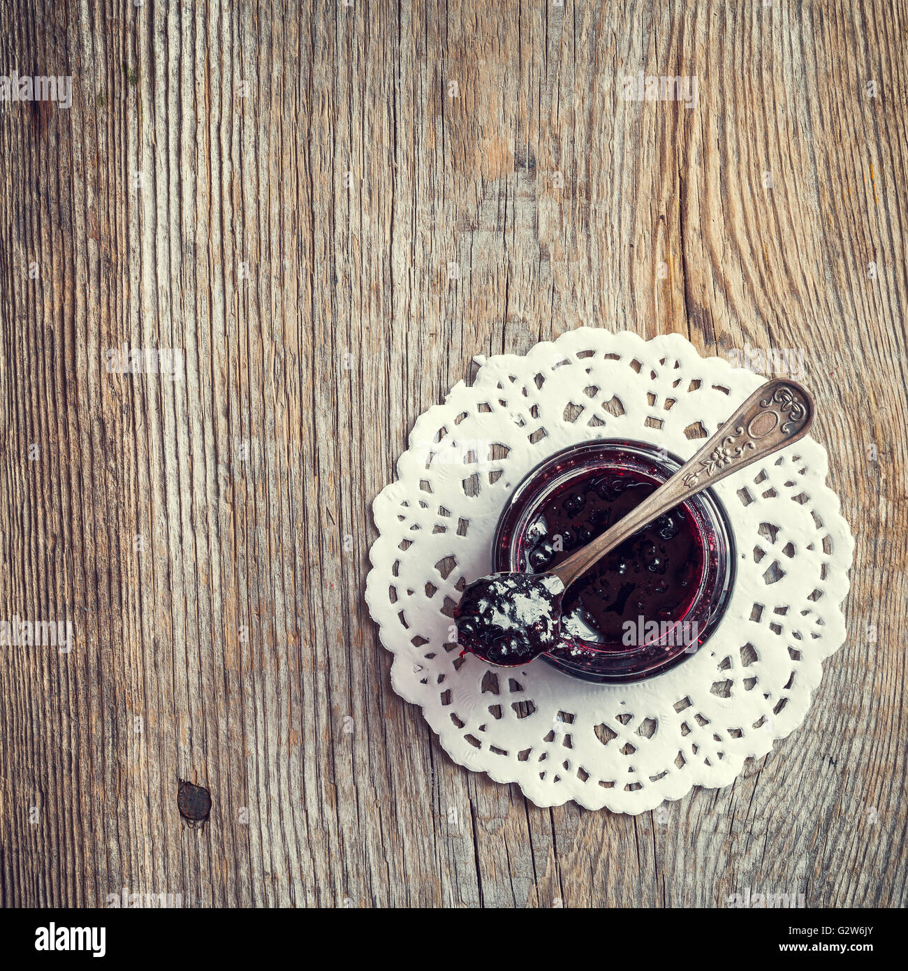 Un vasetto di marmellata con cucchiaio sul vecchio tavolo in legno. Vista dall'alto. Foto Stock