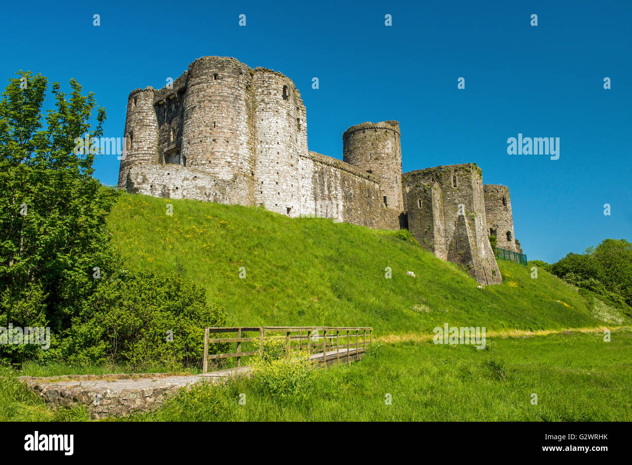 Kidwelly, in gallese, Castello di Cydwelli a Kidwelly, Carmarthensshire Galles del sud, in cielo azzurro, giorno di primavera con ponte di legno Foto Stock