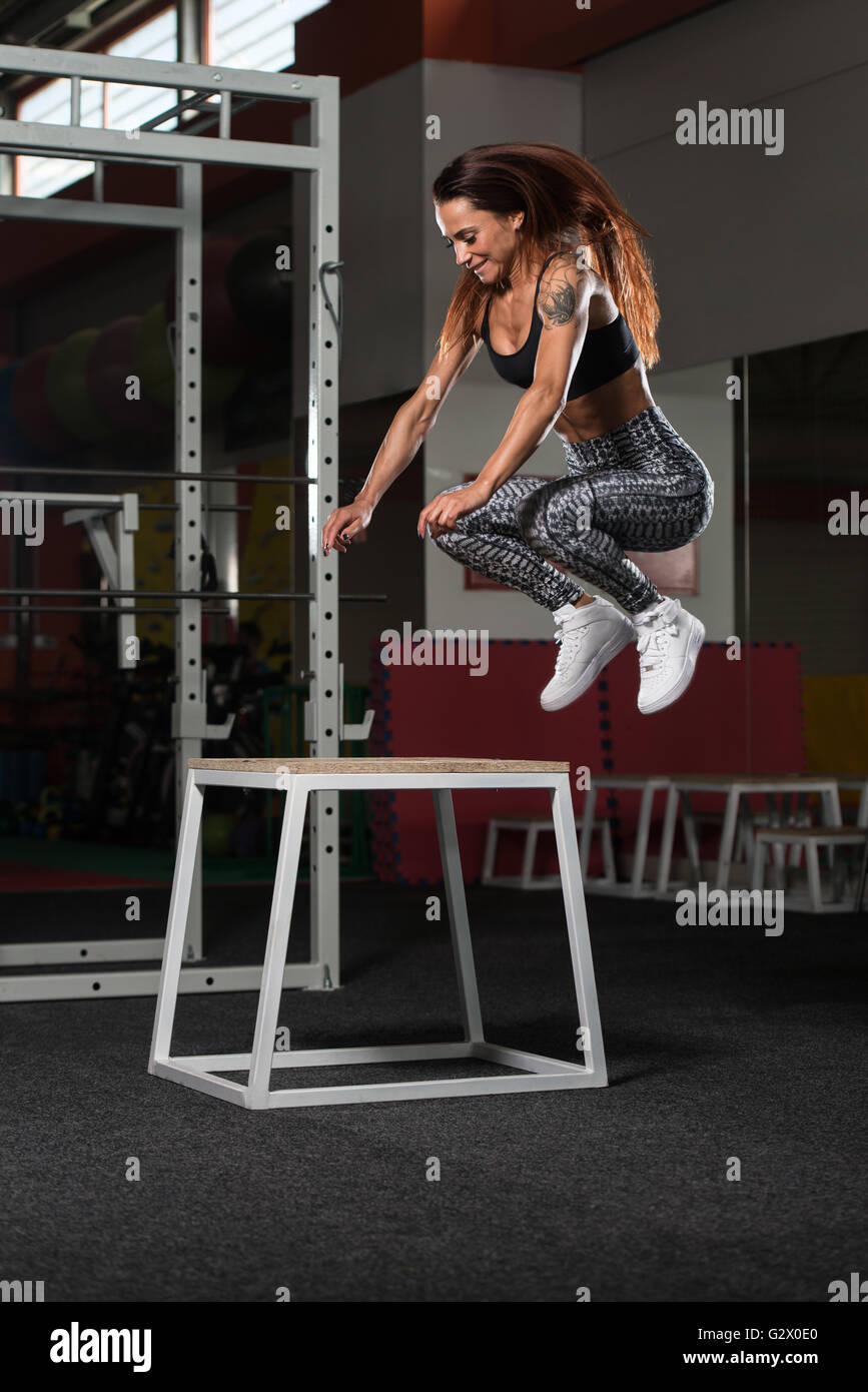 Montare la giovane donna casella facendo saltare in uno stile palestra - atleta femminile è di eseguire la casella Salta in palestra Foto Stock