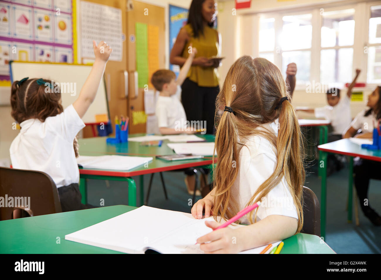 Gli alunni lavorano a banchi di scuola elementare Classroom Foto Stock