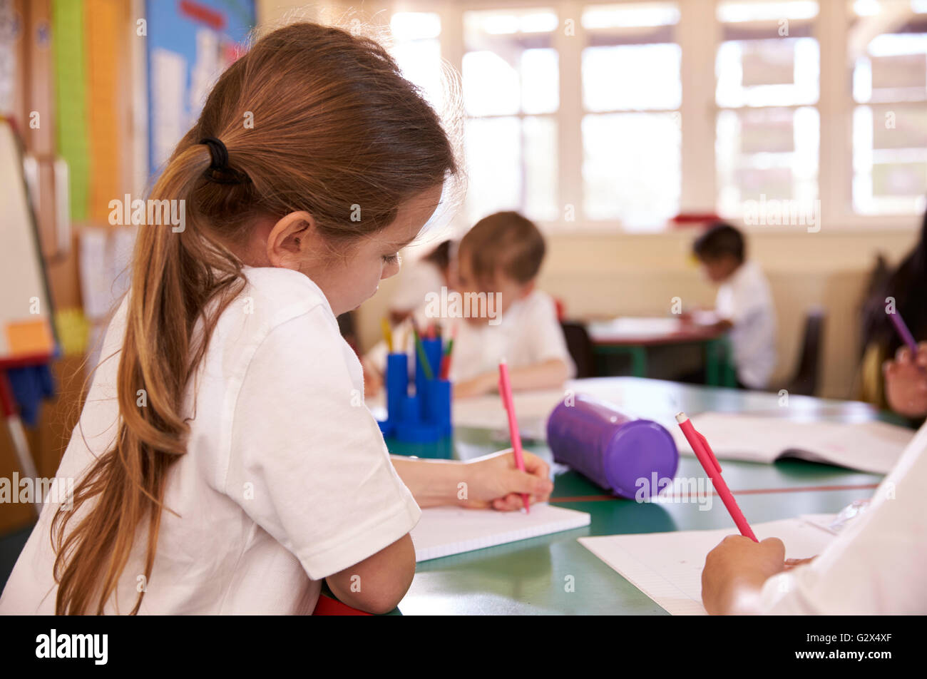 Gli alunni lavorano a banchi di scuola elementare Classroom Foto Stock