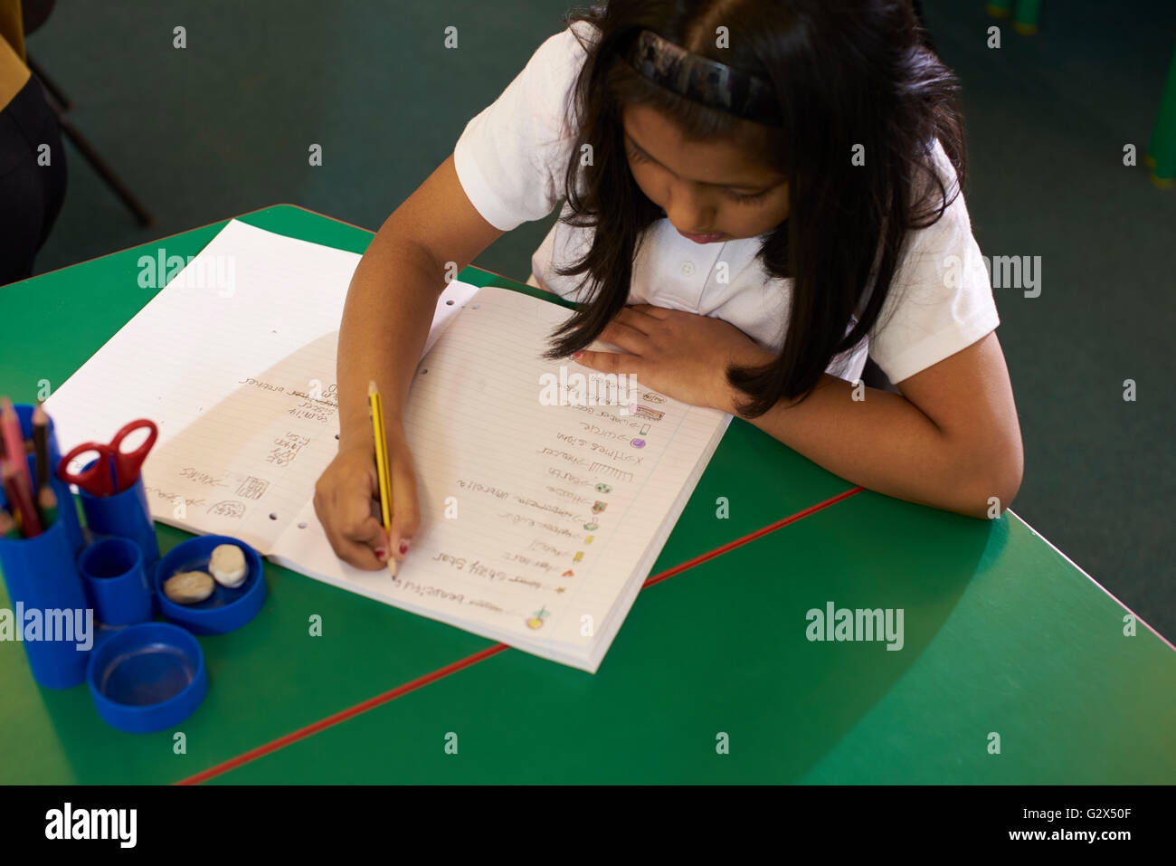 Pupilla d femmina a lavorare alla scrivania nella scuola elementare Classroom Foto Stock
