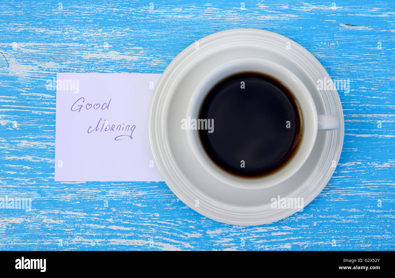 Tazza di tè con buona mattina nota su rustiche in legno di colore blu sullo sfondo. Vista superiore Foto Stock