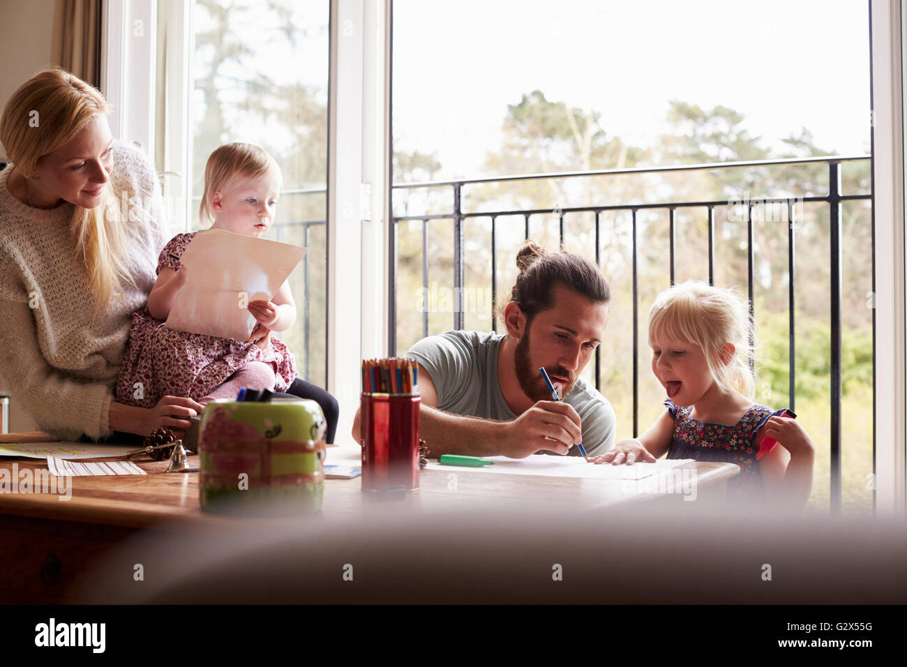 La famiglia seduta a tavola di disegno e foto insieme Foto Stock