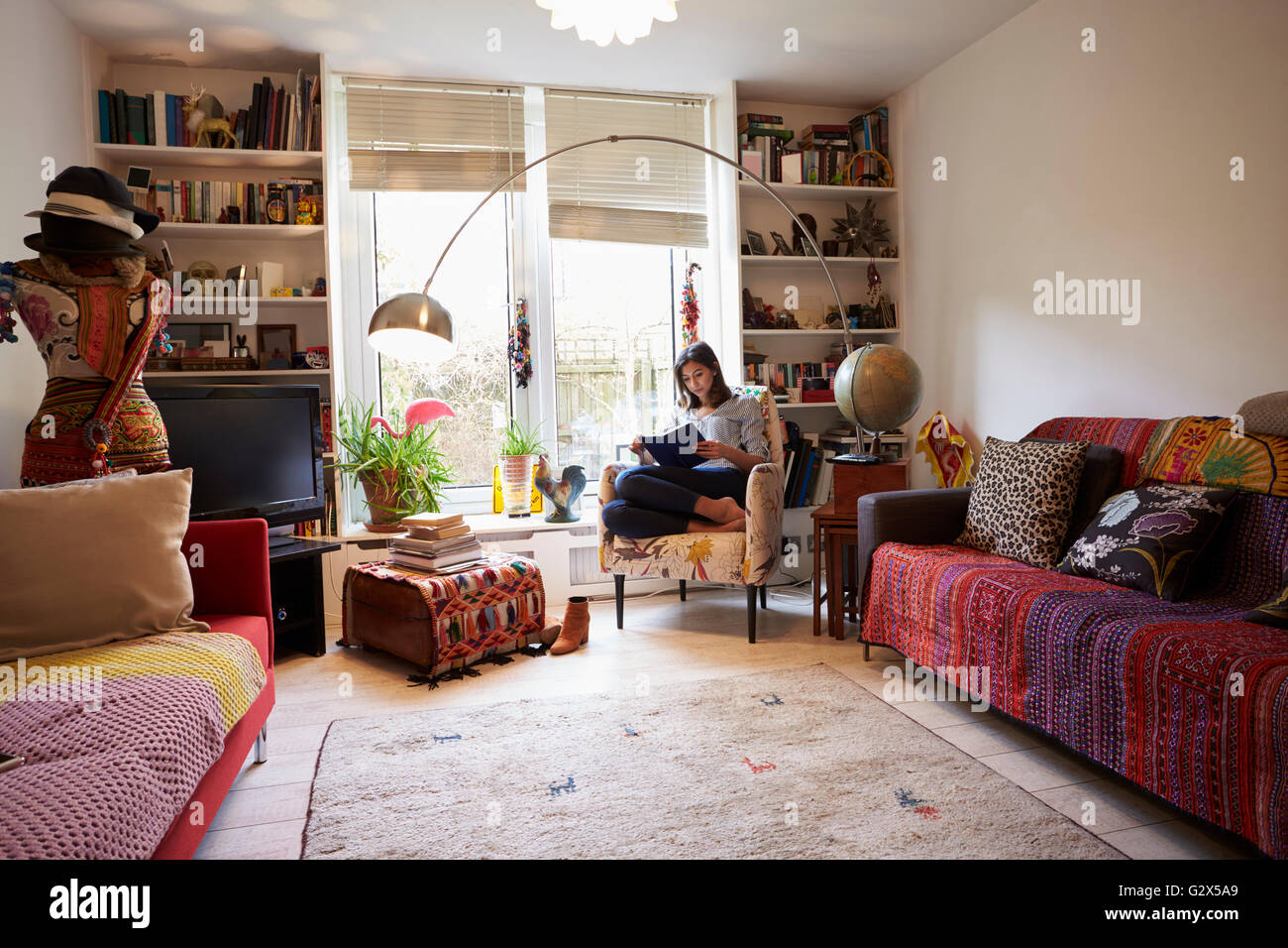 Donna rilassante con Libro In elegante appartamento Foto Stock