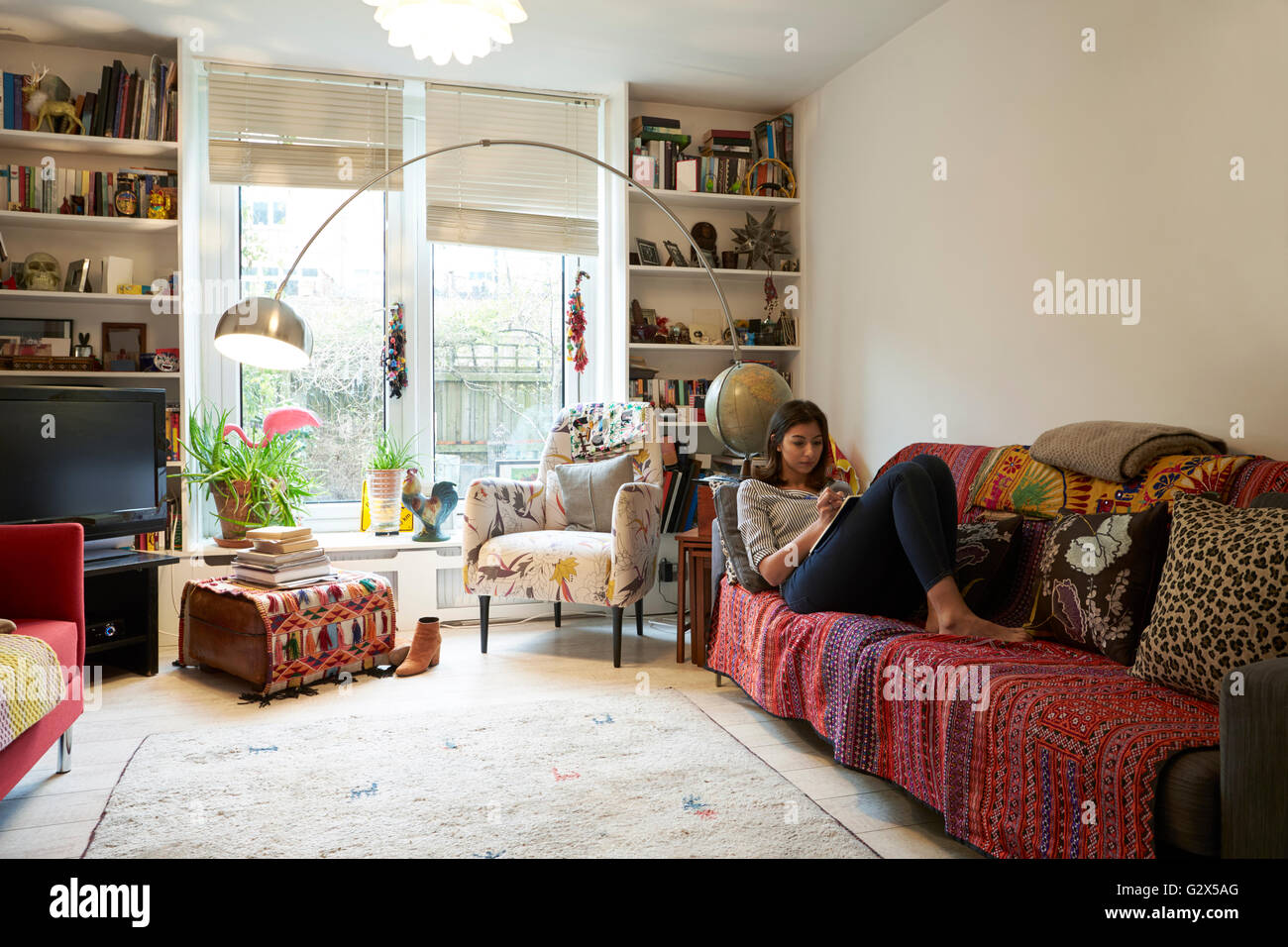 Donna rilassante con Libro In elegante appartamento Foto Stock