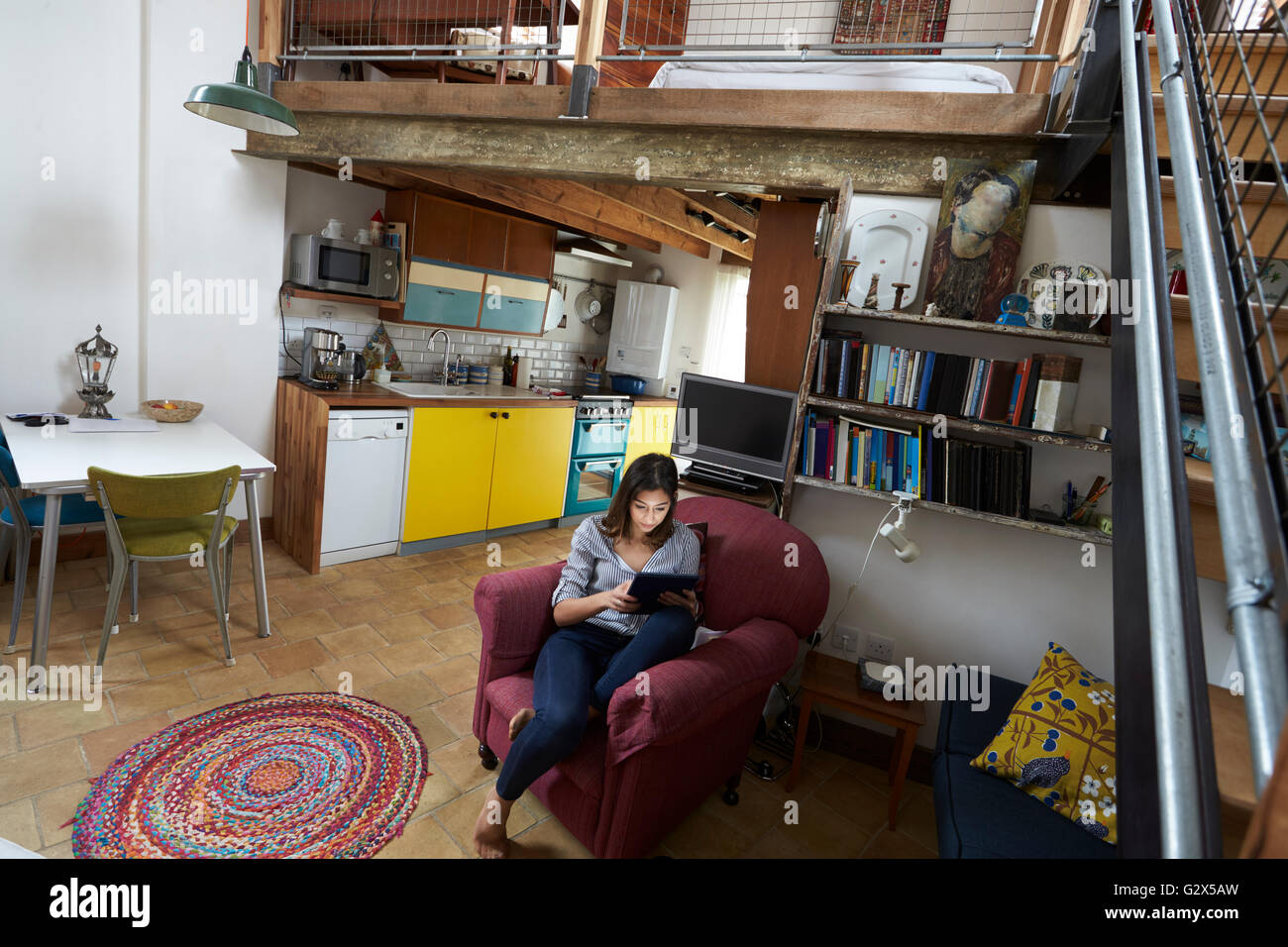 Donna rilassante con tavoletta digitale In elegante appartamento Foto Stock
