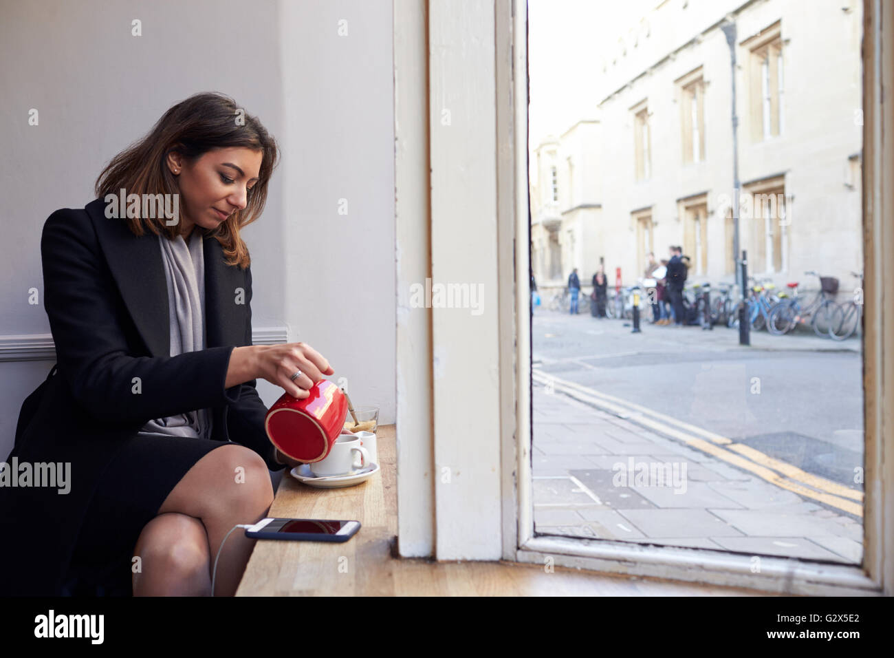 Imprenditrice rilassante con tazza di tè al Café Foto Stock