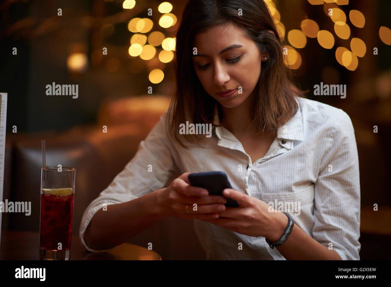 Imprenditrice utilizzando il telefono cellulare nel bar dopo il lavoro Foto Stock
