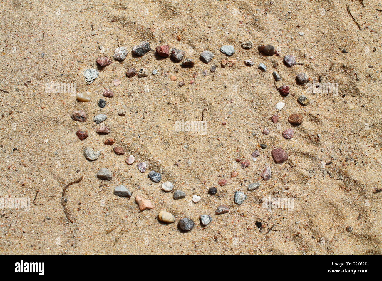 Simbolo di amore il cuore da piccoli sassi sulla calda sabbia della spiaggia Foto Stock