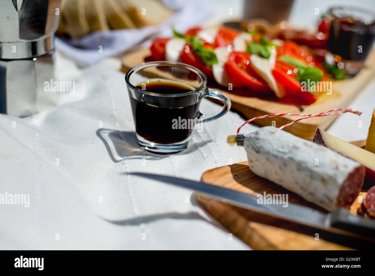 Una tazza di caffè tra un picnic esterno dell'insalata e salame Foto Stock