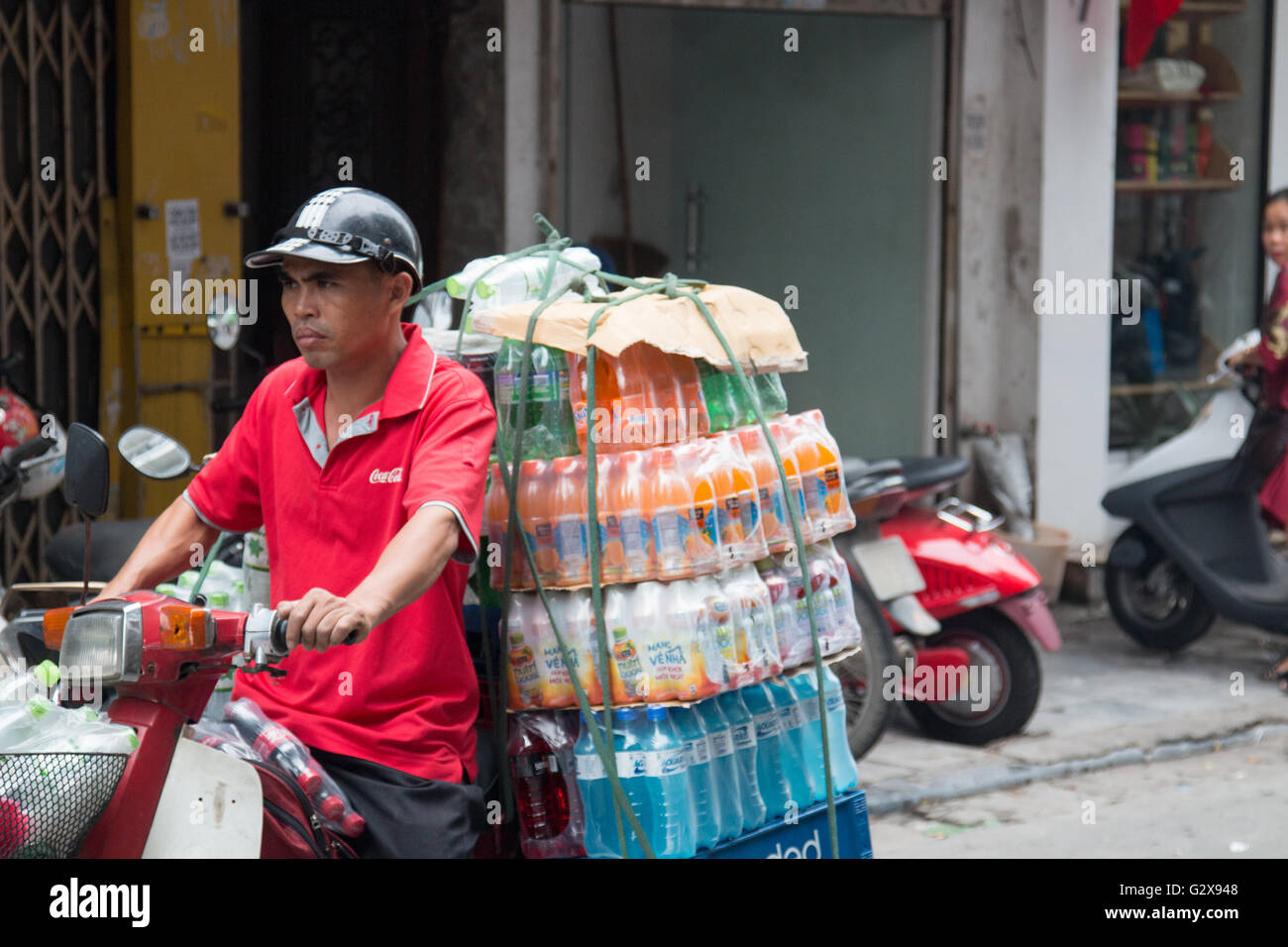 Uomo vietnamita di equitazione Trasporto scooter soft drink bottiglie in Hanoi old quarter,Vietnam,Asia Foto Stock