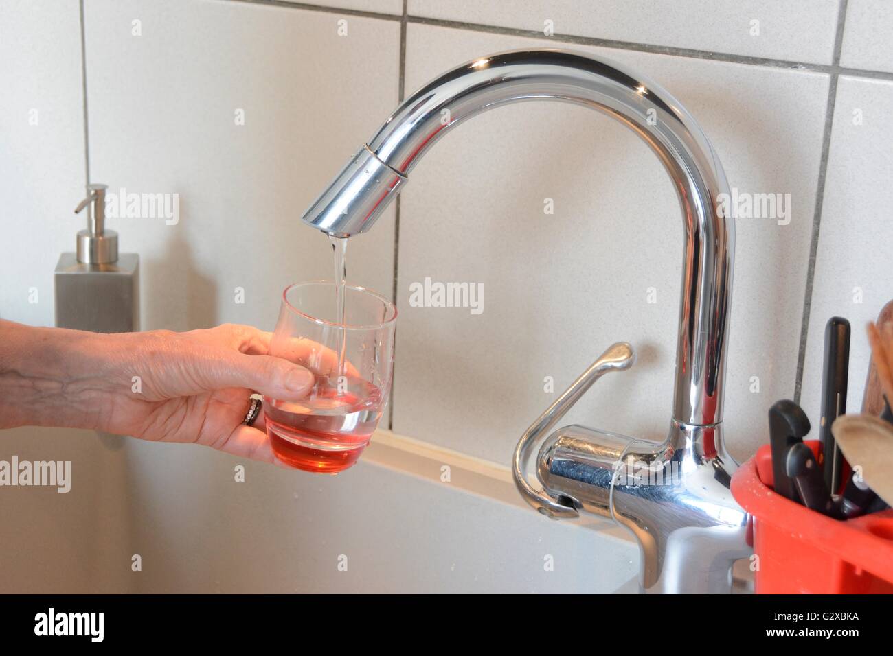 Riempire un bicchiere con acqua di rubinetto in una cucina, Francia Foto Stock