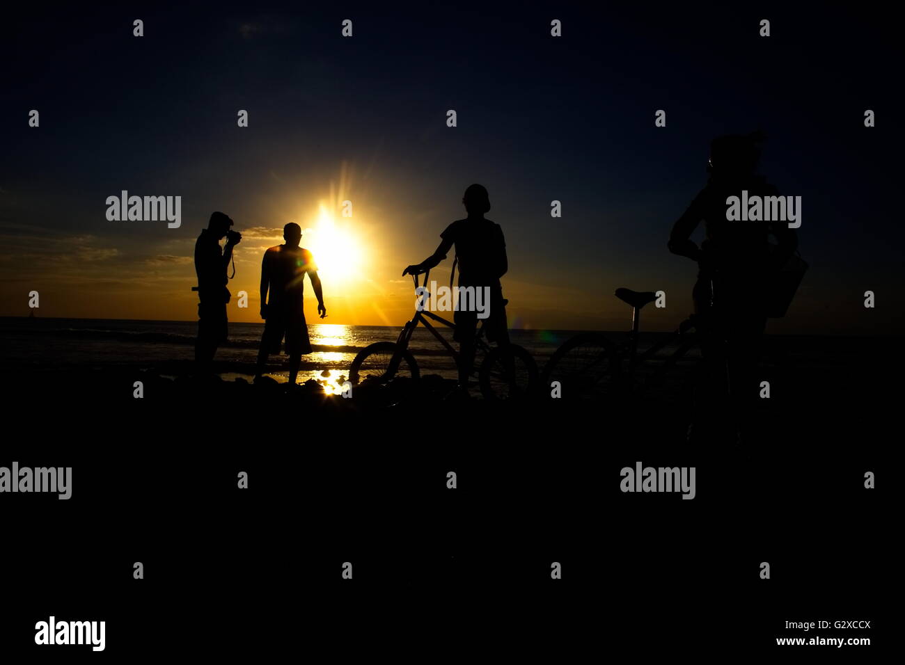Ciclista, fotografo e bagnanti al tramonto sulla spiaggia di Playa de las Americas, Tenerife, Isole Canarie, Spagna, Europa Foto Stock