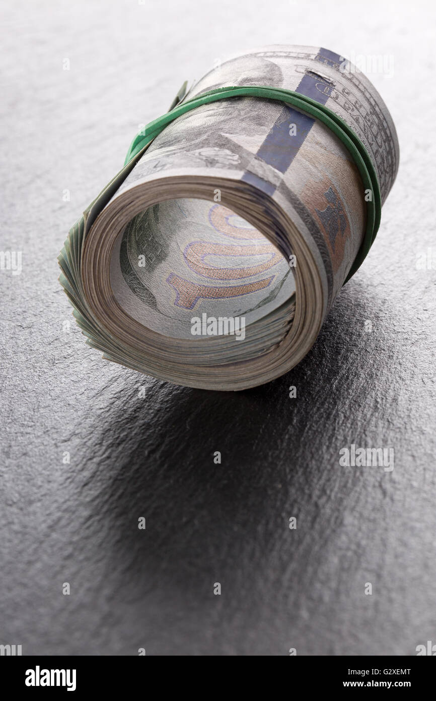 Rotolo di denaro di dollari su una tavola di ardesia. Foto Stock