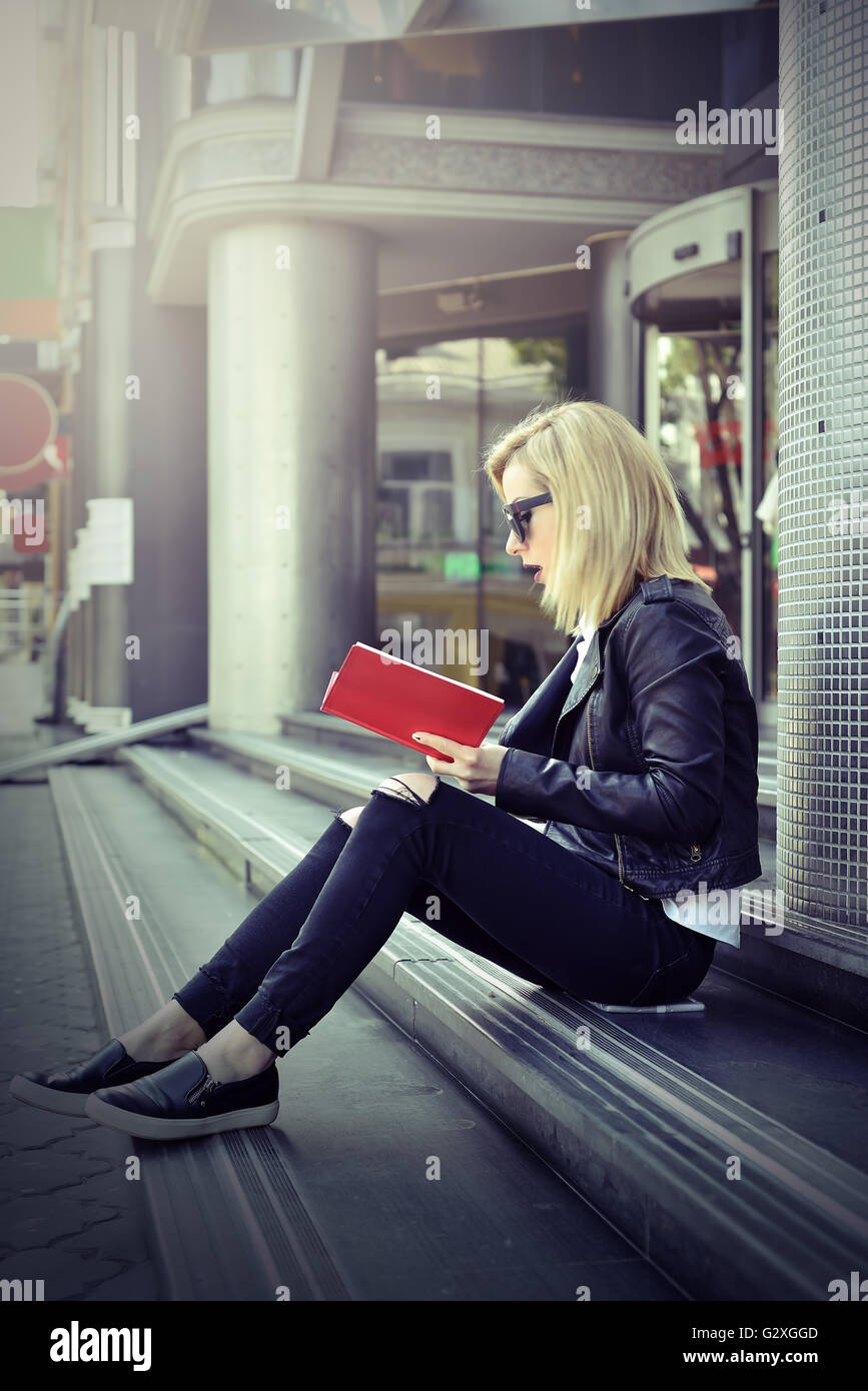 Giovane ragazza hipster leggendo un libro rosso. effetto tonico Foto Stock