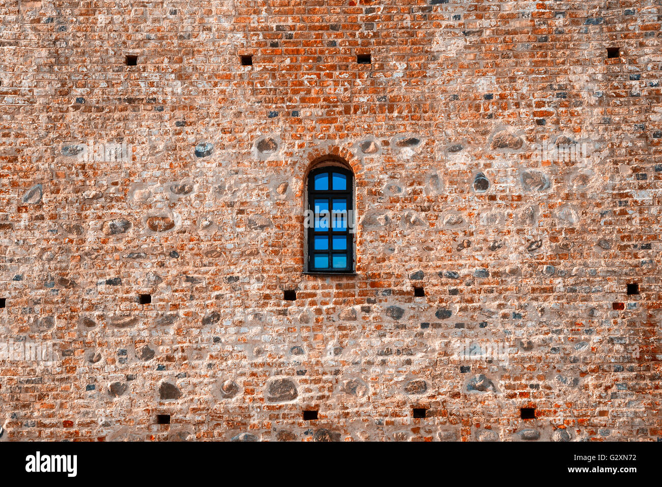 Finestra ad arco in un età compresa tra i mattoni rossi muro di castello Foto Stock
