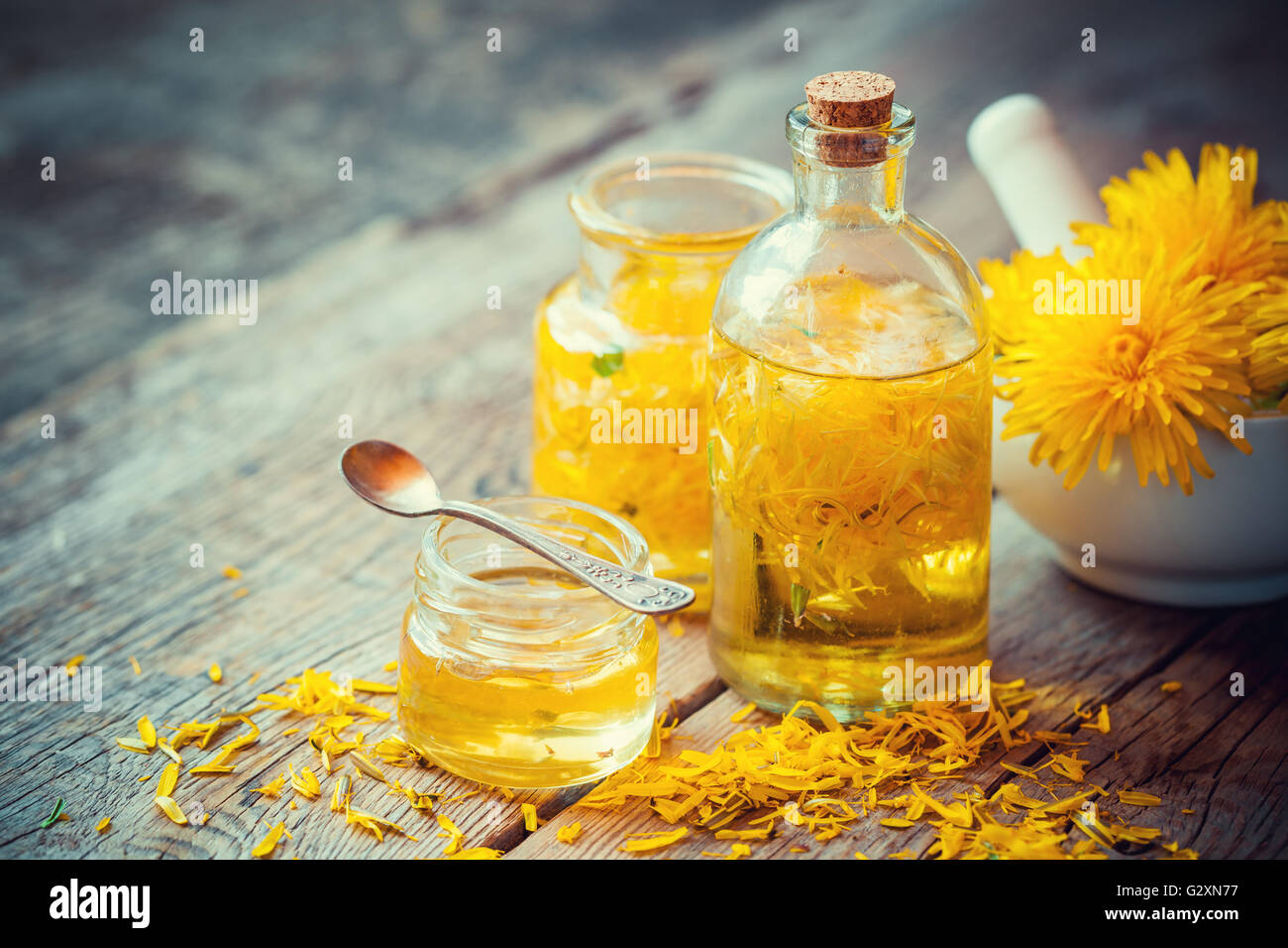 Tarassaco tintura o bottiglie di olio, malta e miele sul tavolo. La medicina di erbe. Foto Stock