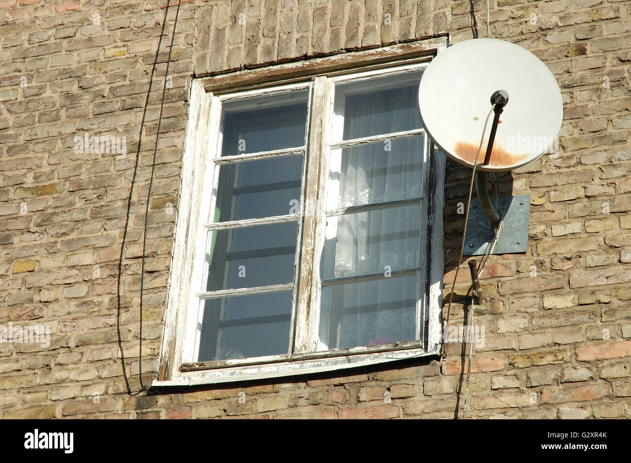 Vecchio bianco finestra in legno nel muro di mattoni e una vecchia parabola  satellitare Foto stock - Alamy