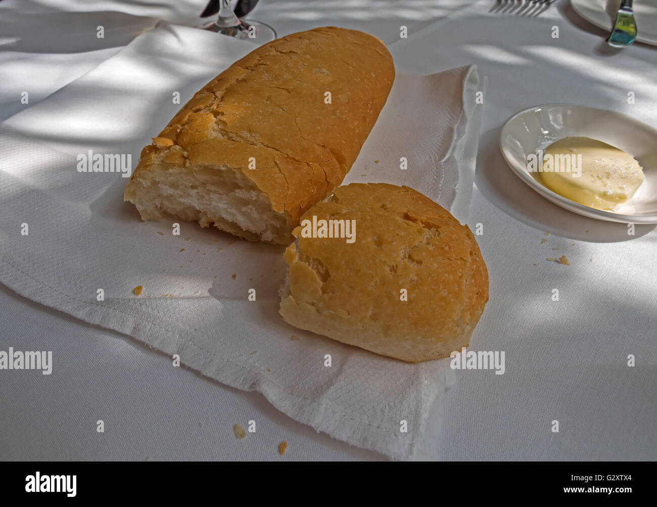 Crostini di pane bianco con un piatto di burro su una tovaglia bianca Foto Stock