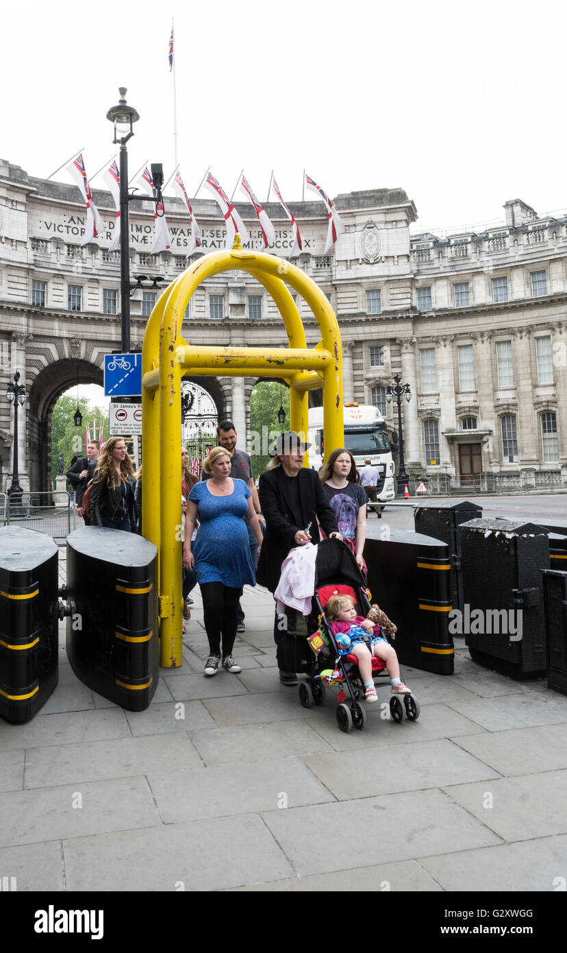 Una donna incinta e una famiglia che passa attraverso una barriera di sicurezza di fronte all'Admiralty Arch e all'Old War Office, Whitehall, Londra, Inghilterra, Regno Unito Foto Stock