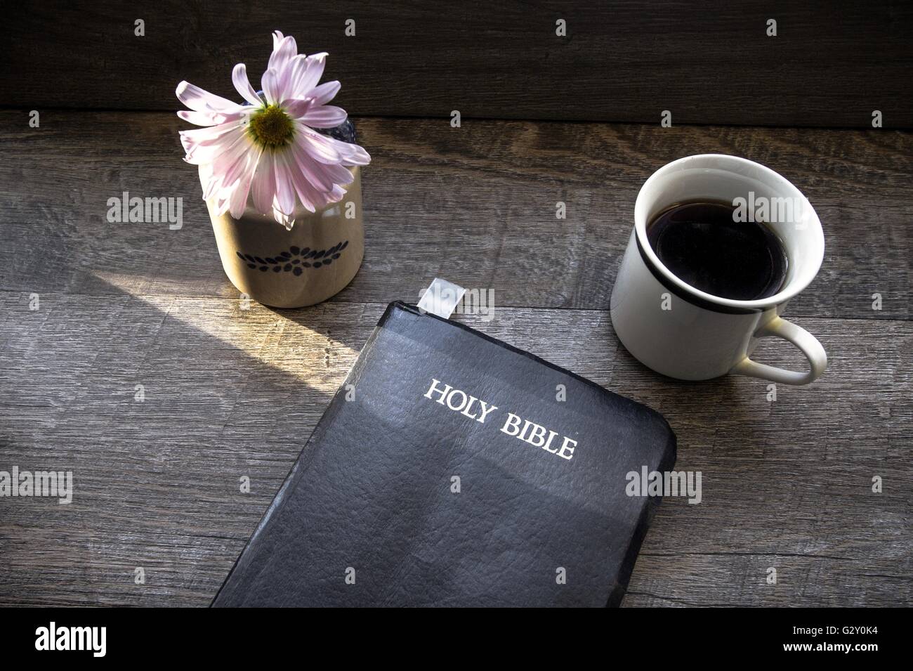Il caffè al mattino con la bibbia illuminata dalla luce del sole. Tazza di caffè con la Bibbia cristiana illuminata da un raggio di sole. Foto Stock