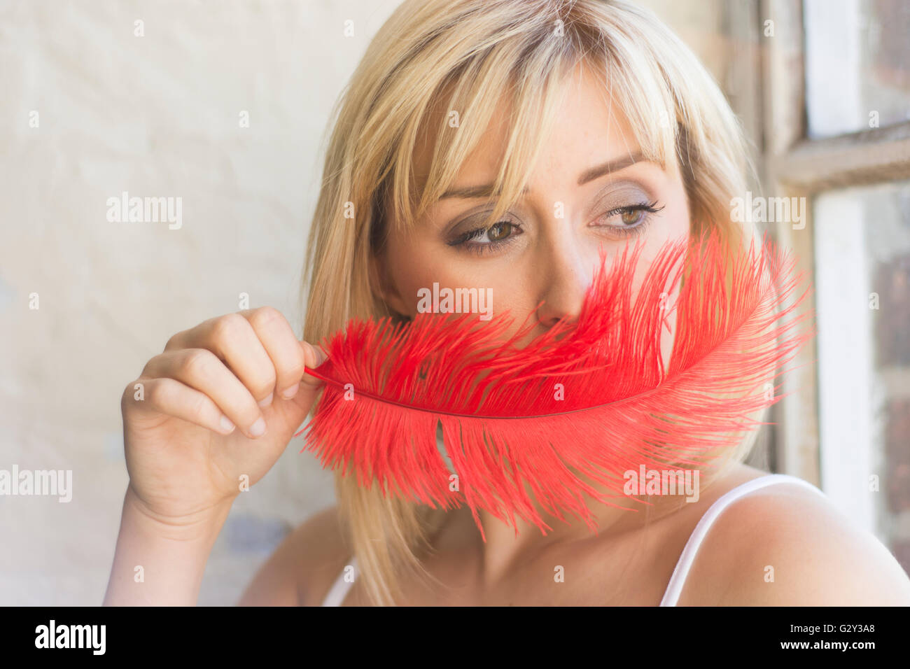 Giovane donna nasconde il viso con un red feather Foto Stock