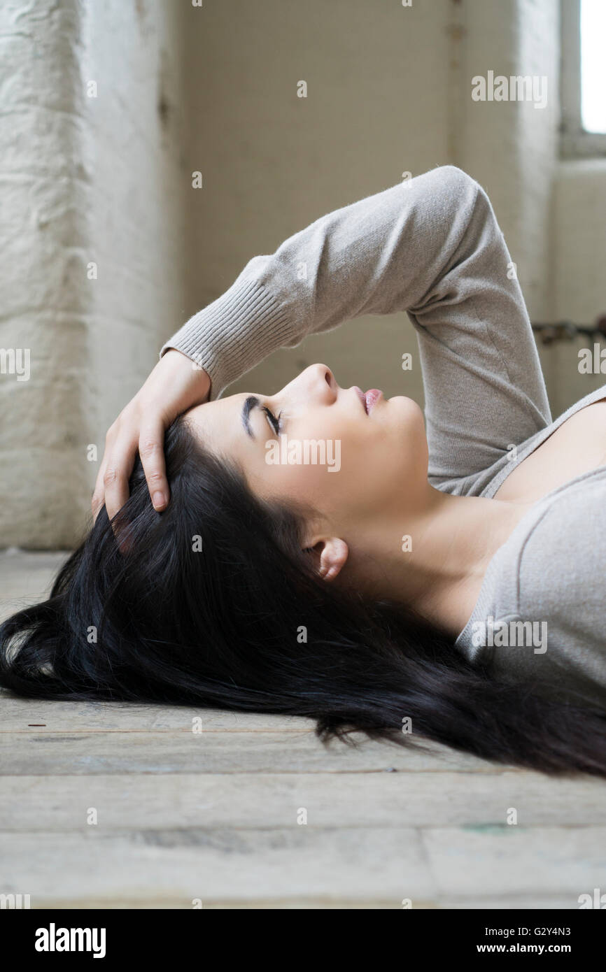 Grave giovane donna posa sul pavimento cercando Foto Stock