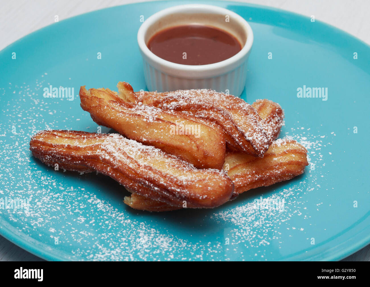 Churros sulla piastra blu con salsa di cioccolato Foto Stock