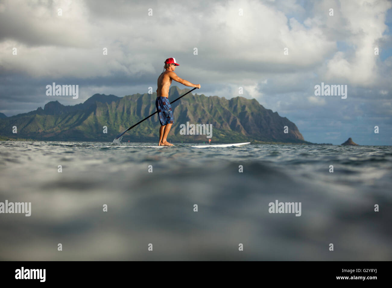 Viste dal mattino stand up paddle board session a Kaneohe Bay, Brad Osborn paddling tropicale scheda di miscele di sunrise. Foto Stock