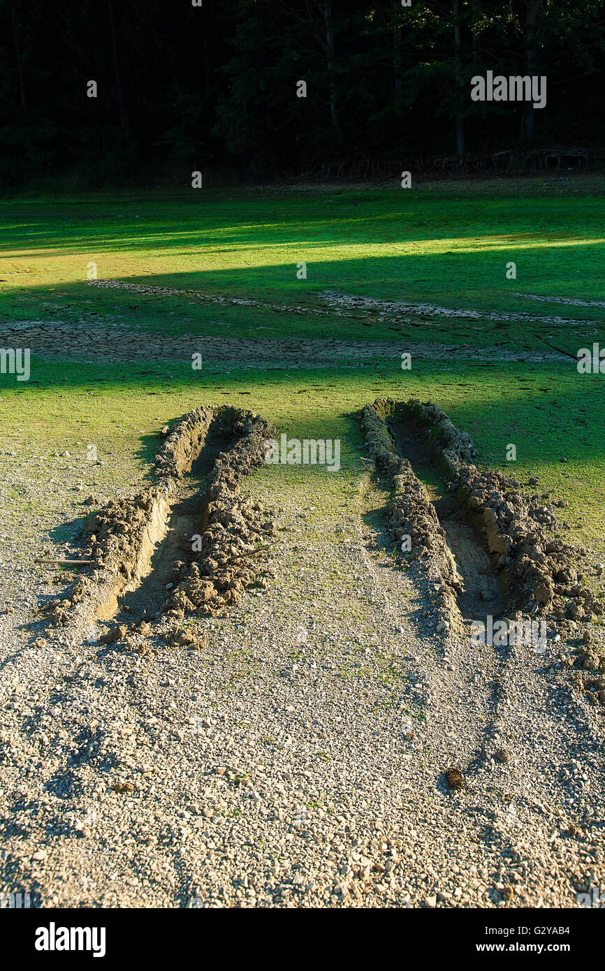 Le tracce delle ruote della vettura sulla riva del lago. Foto Stock