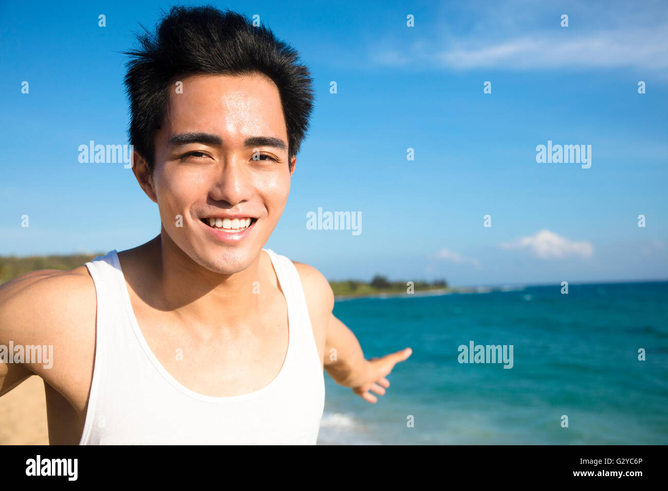Rilassante e sorridente giovane uomo sulla spiaggia Foto Stock