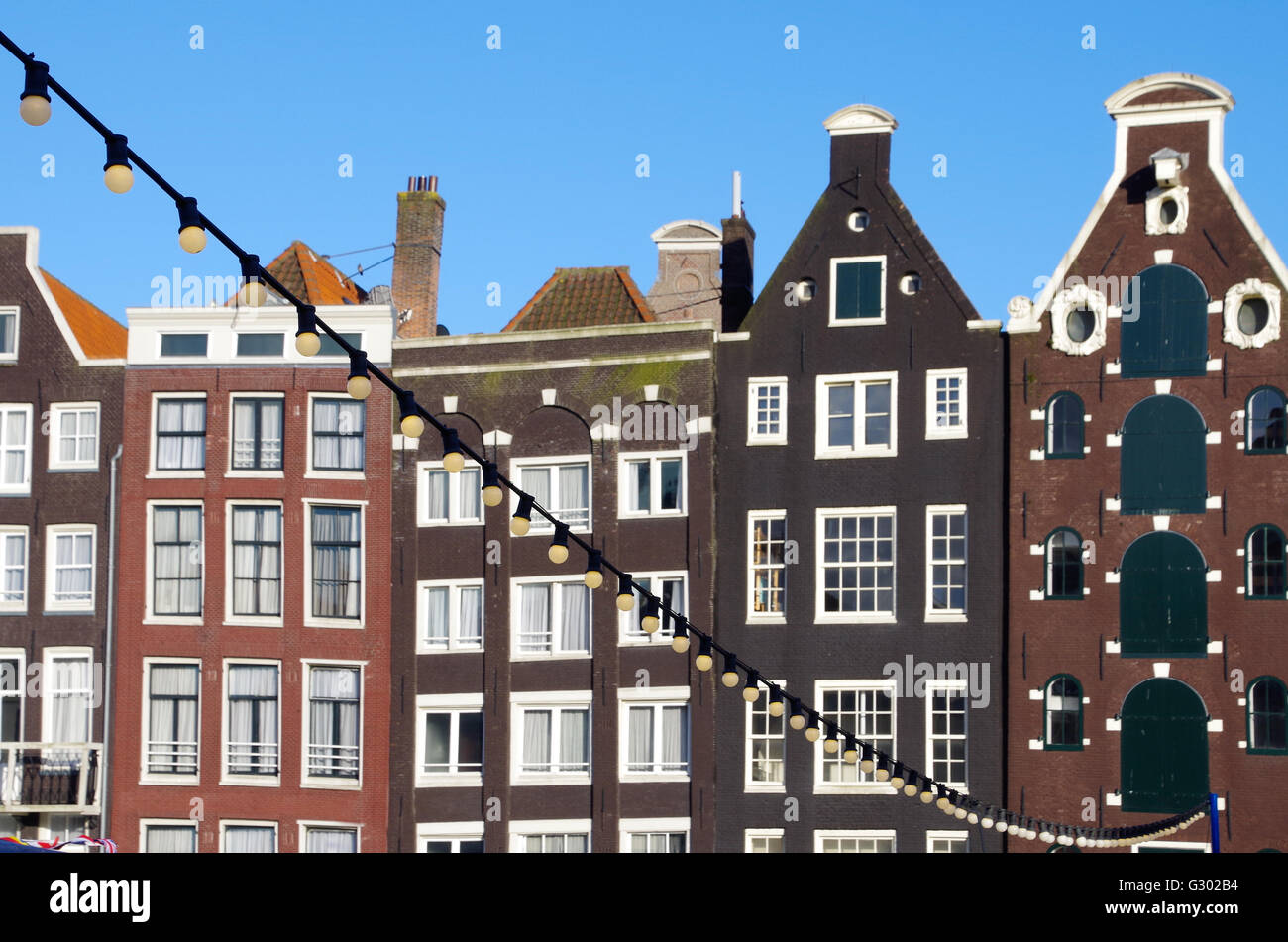 Globo luci stringa appeso sopra un canale di Amsterdam con le tipiche case di Amsterdam in background Foto Stock
