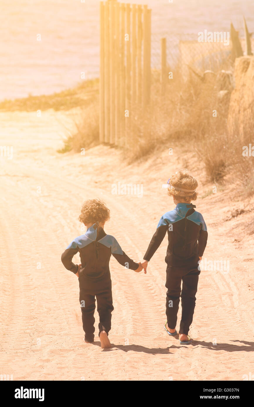 Due fratelli di camminare sulla spiaggia visto da dietro Foto Stock