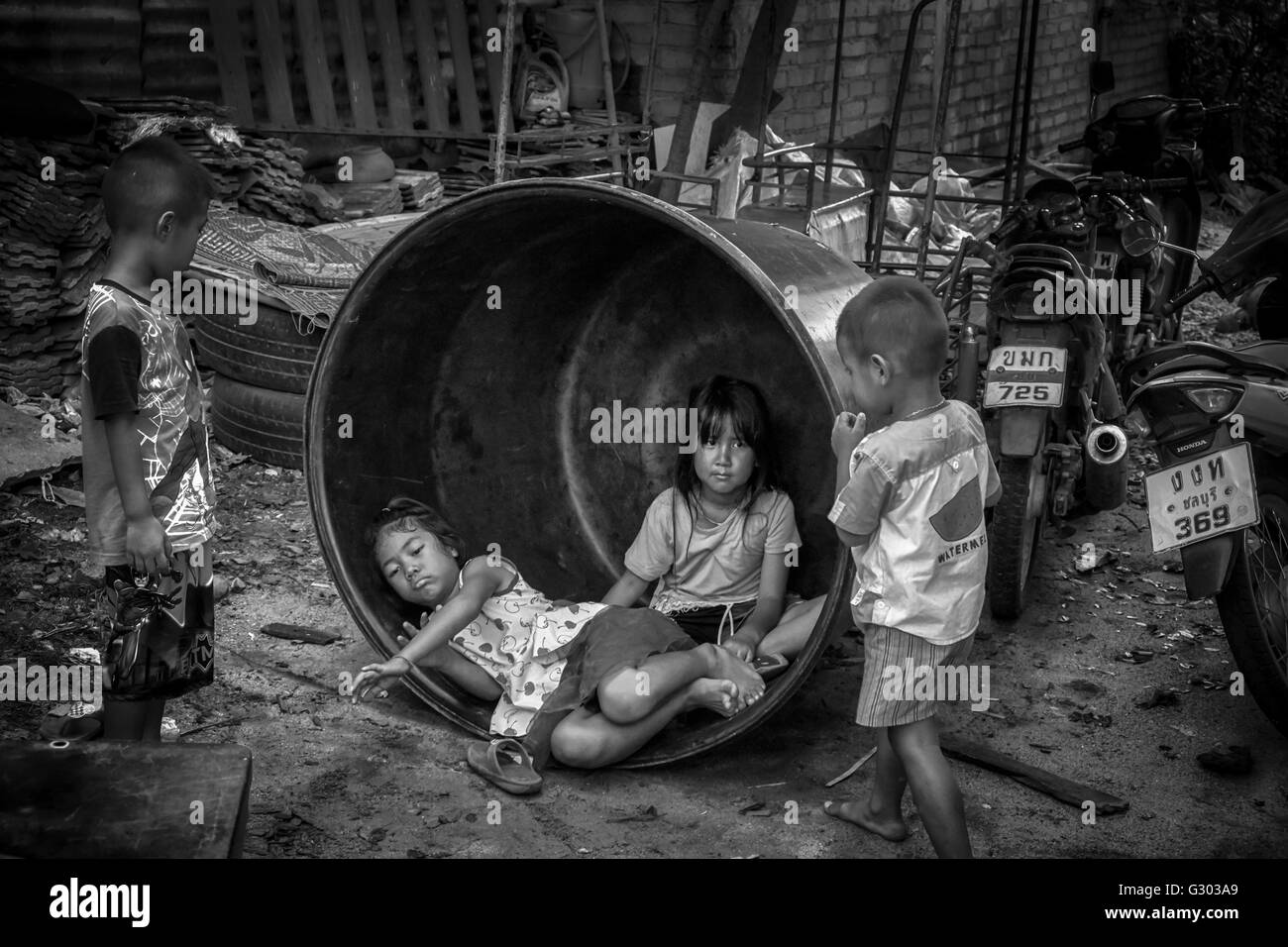 Thailandia povertà. Bambini che giocano tra le macerie in una backstreet tailandese. Thailandia S. E. Asia. Bambini slum. Fotografia in bianco e nero Foto Stock