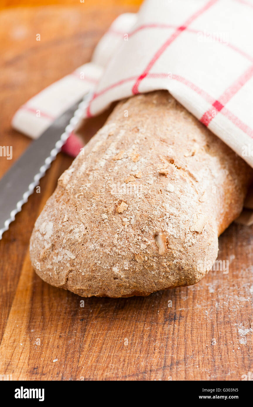 Nuovo filone di pane e coltello da cucina su un tagliere di legno Foto Stock