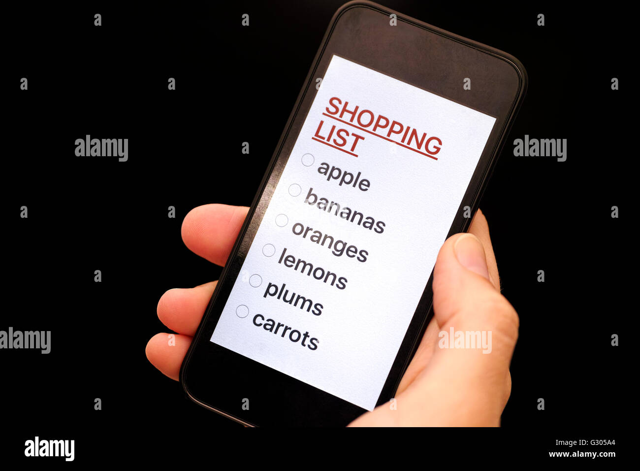 Shopping List su smart display del telefono nella donna la mano. Sfondo nero. Foto Stock