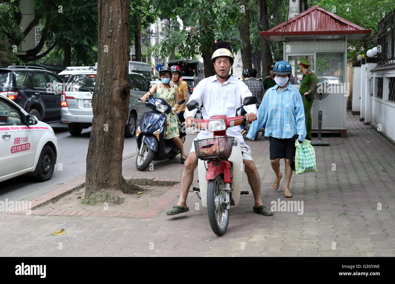 Persone a cavallo scooter sul marciapiede di traffico Foto Stock