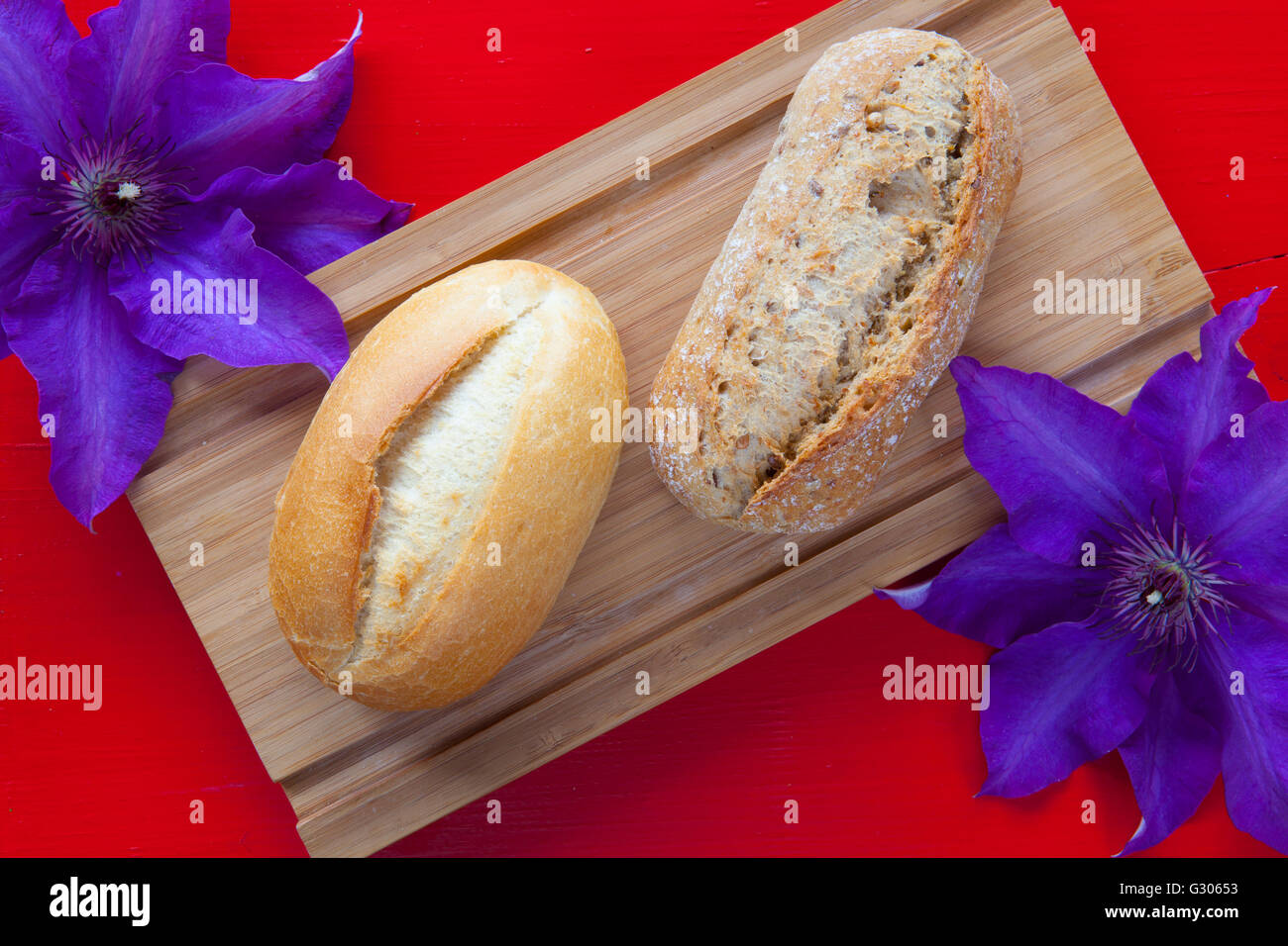 Fragrante colazione - Due pane di frumento e clematis fiore sulla scrivania in legno Foto Stock