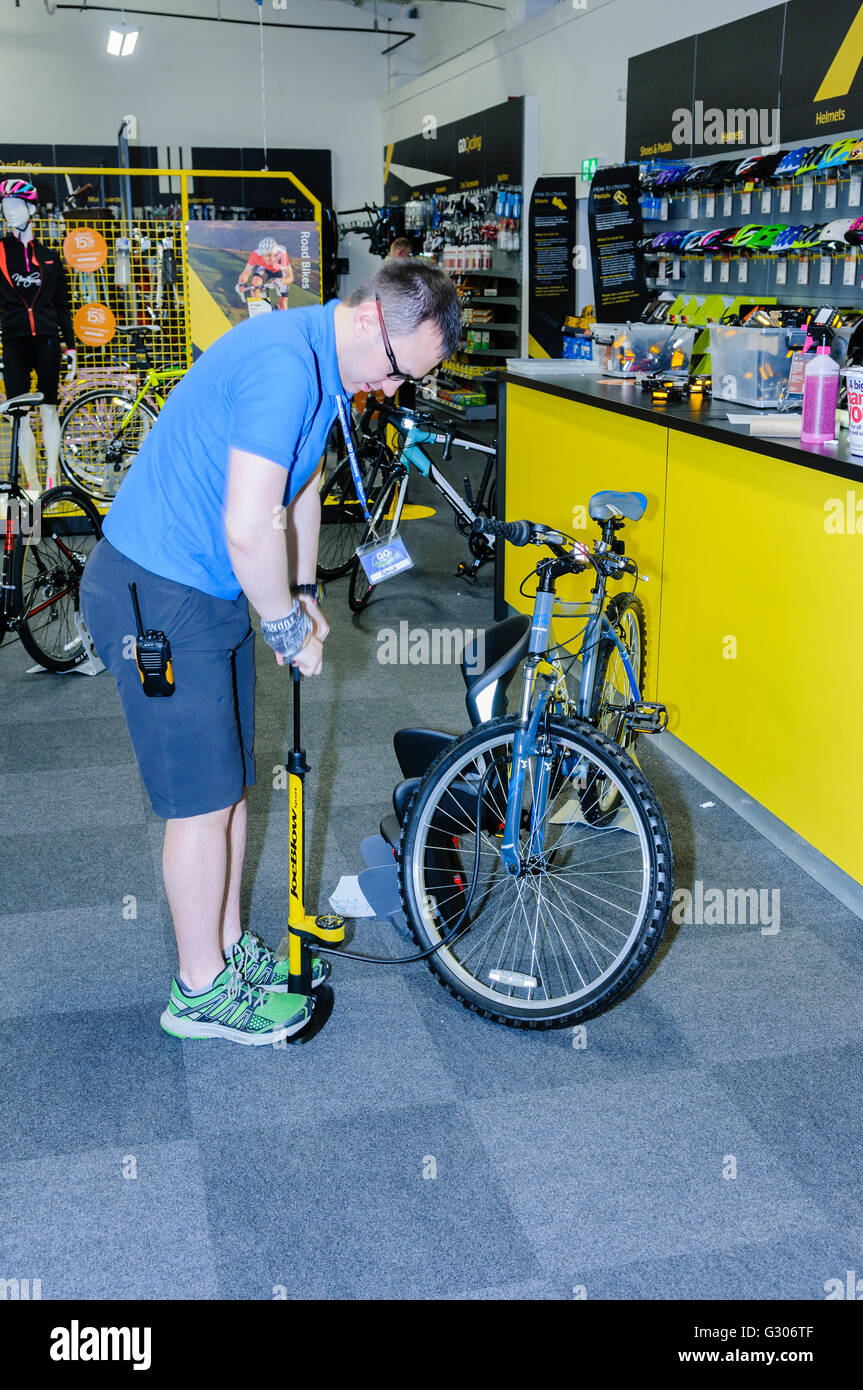 Un membro del personale prepara una bicicletta per la vendita nel ciclismo la sezione di andare all'aperto sport shop. Foto Stock
