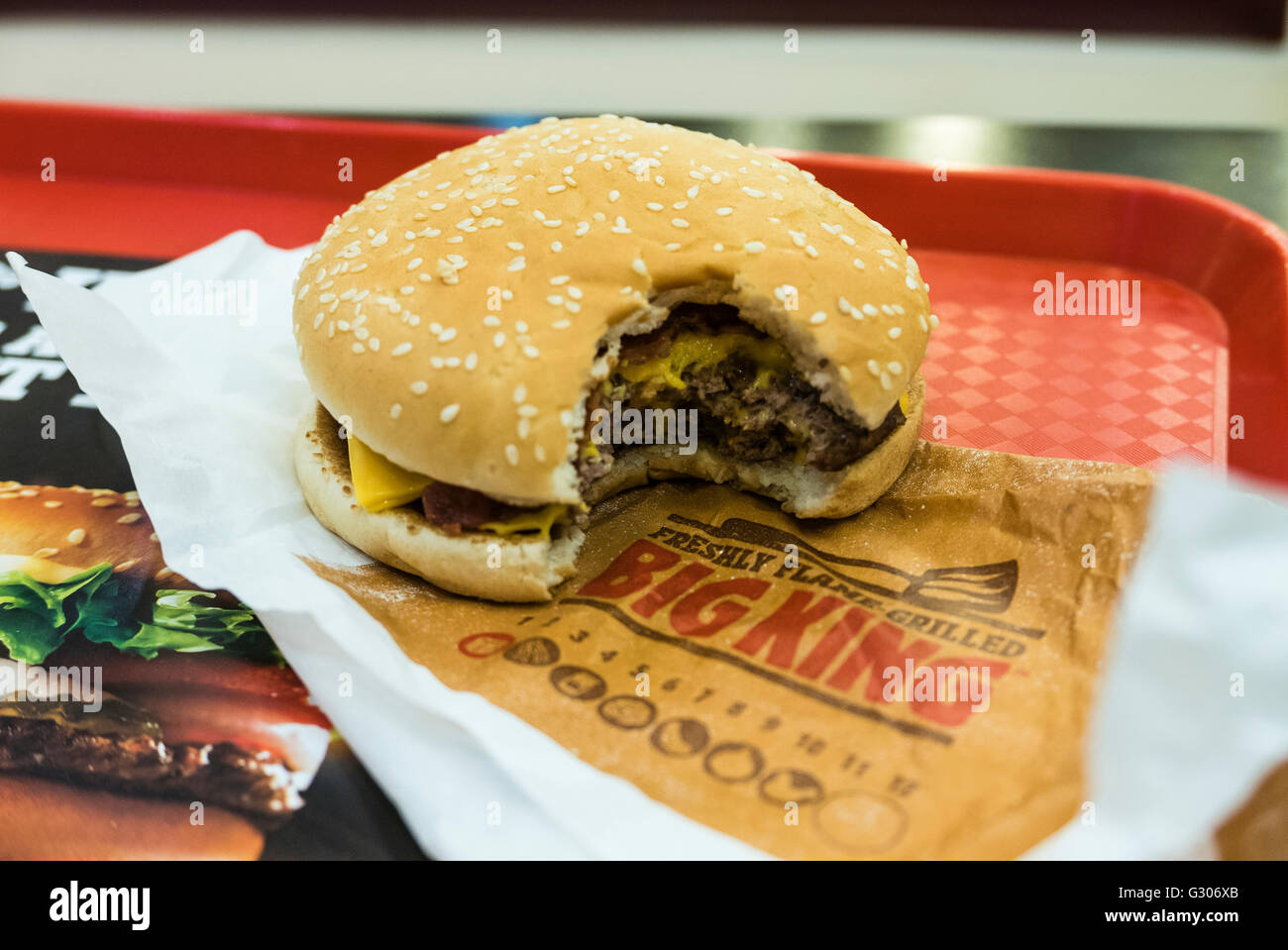 Hamburger con un morso preso fuori di esso, su un vassoio in un Burger King e un ristorante fast-food. Foto Stock
